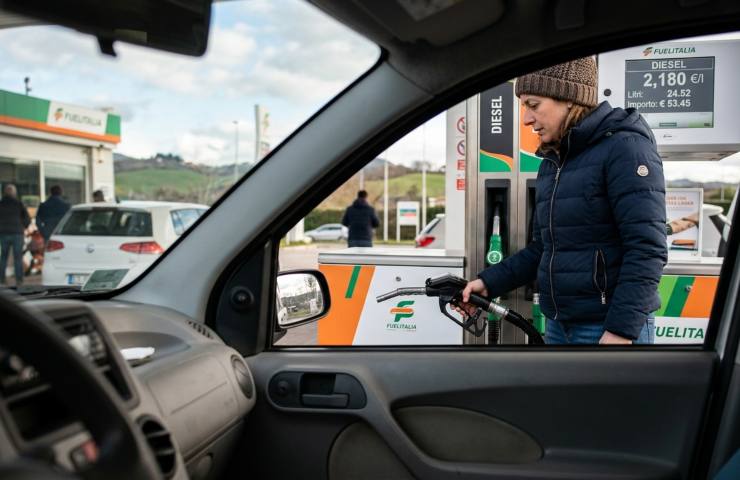 Donna rifornisce auto Fiat Panda presso distributore FuelItalia, 11 aprile 2026. Primo piano sul display della pompa che mostra il prezzo del Diesel a 2,180 €/l. Inquadratura dall'interno dell'abitacolo (POV) che cattura il momento dell'erogazione carburante. Foto realistica e attuale per news su costi benzina e gasolio oggi in Italia.