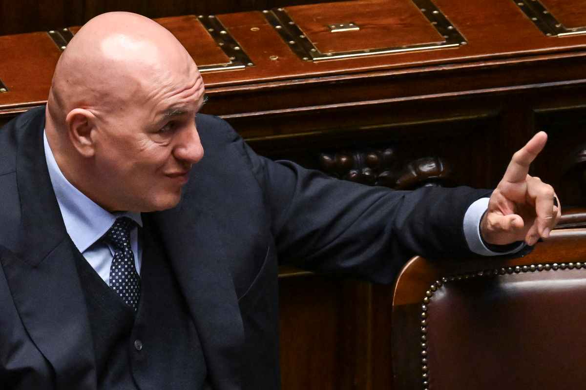 Il Ministro della Difesa, Guido Crosetto, sorride mentre inquadrato di profilo in Parlamento.