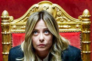 Giorgia Meloni seduta in Parlamento con lo sguardo rivolto verso l'alto.