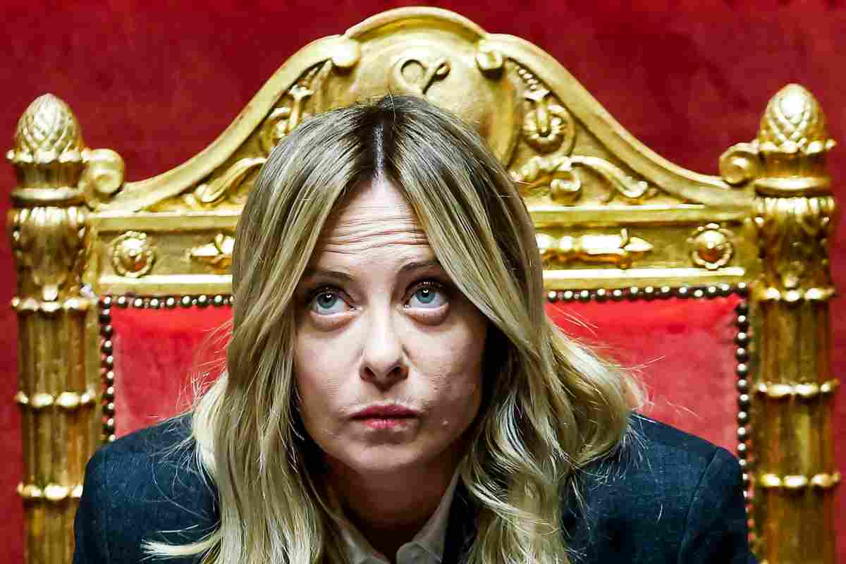 Giorgia Meloni seduta in Parlamento con lo sguardo rivolto verso l'alto.