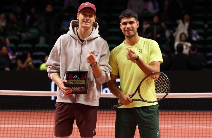 Jannis Sinner con un premio a sinistra e Carlos Alcaraz con una racchetta mentre posano insieme sorridenti.